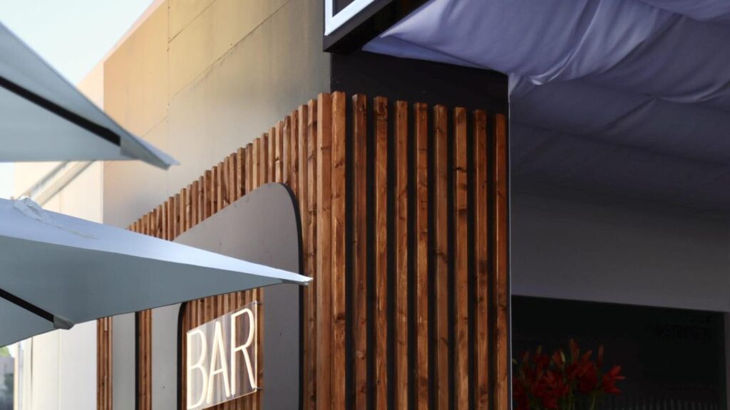 Warmly designed exhibition stand with a timber-slat bar and soft lighting